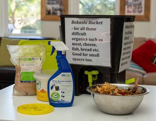 Bokashi bucket on table with cleaning products and scraps