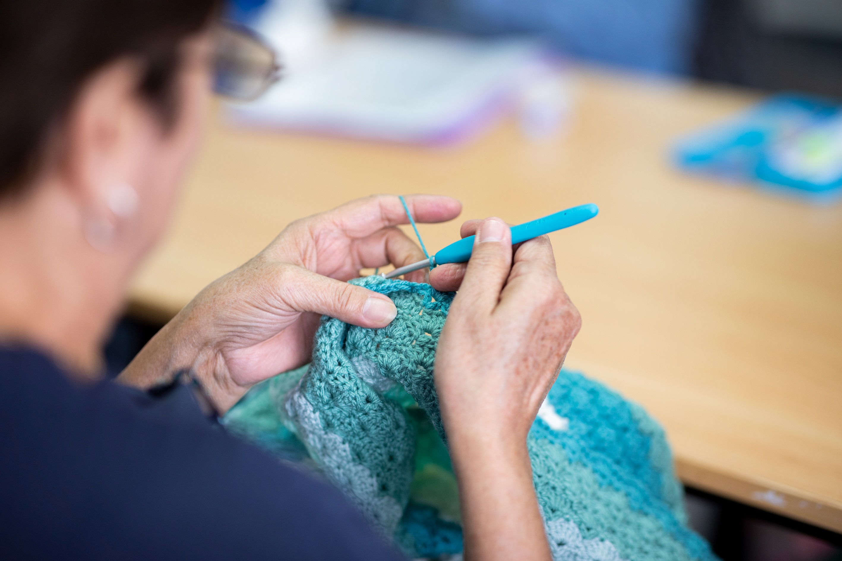 A person crocheting with aqua wool