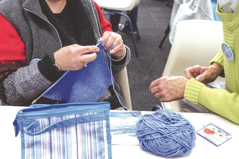 A person knitting with blue wool