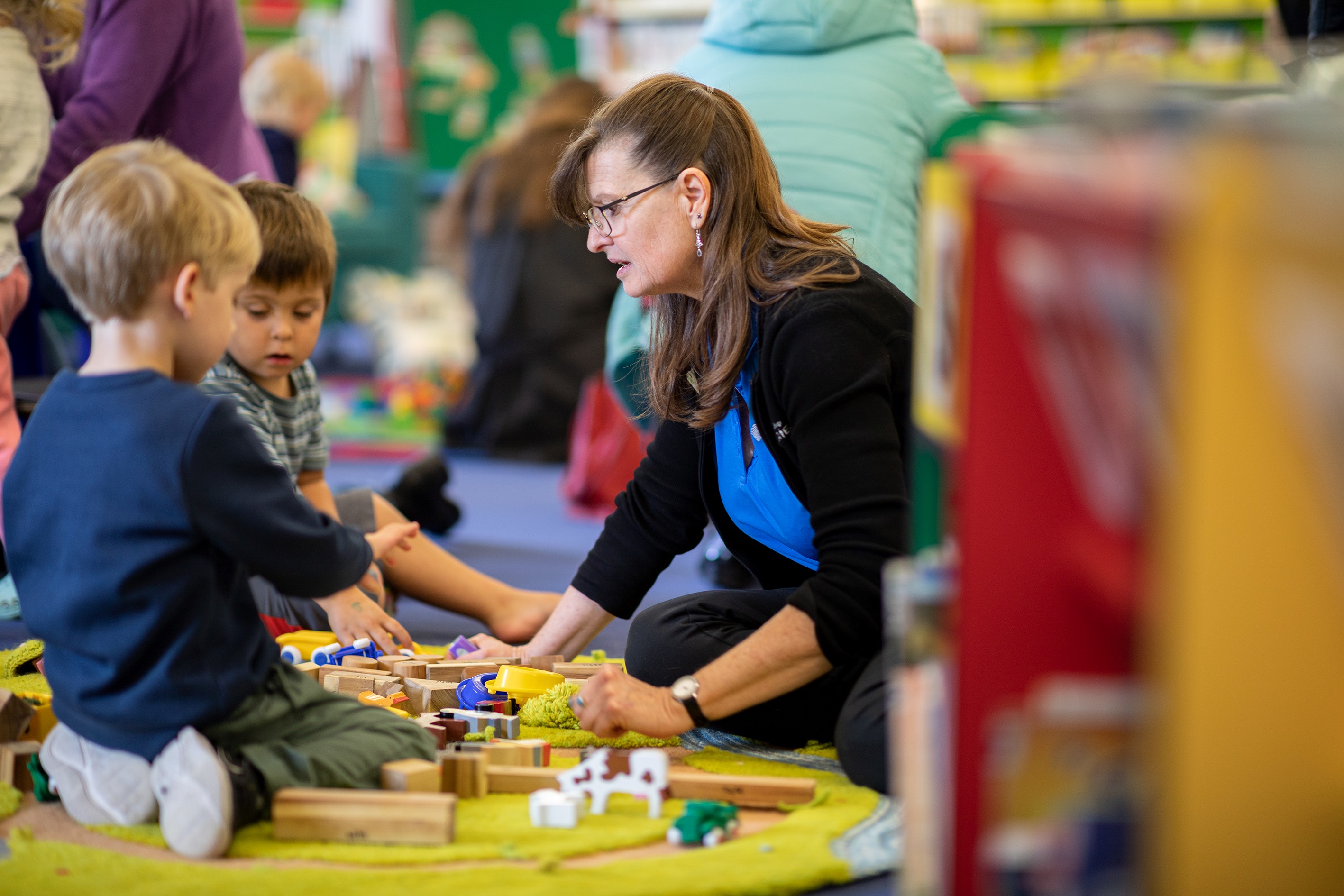 Two young children and a librarian playing with wooden blocks