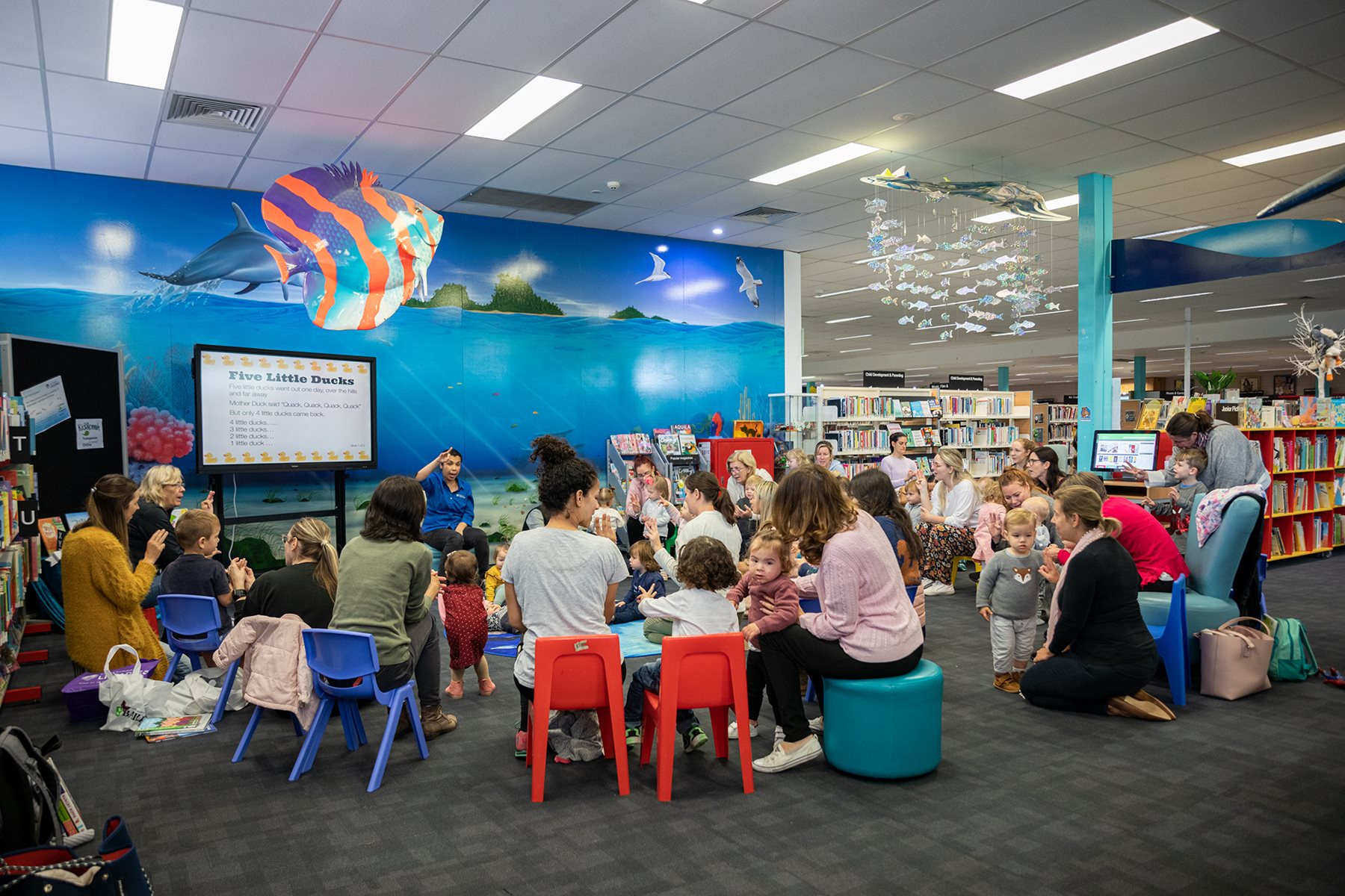 A librarian reading an early childhood book to a group