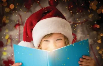 Little girl with a santa hat holding a big book